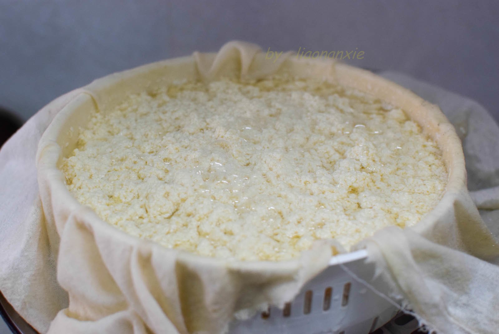 Trải vải màn trong rổ thoát nước, múc đậu hũ non vào. Gói lại bằng vải, đặt tấm nặng lên trên để ép định hình.