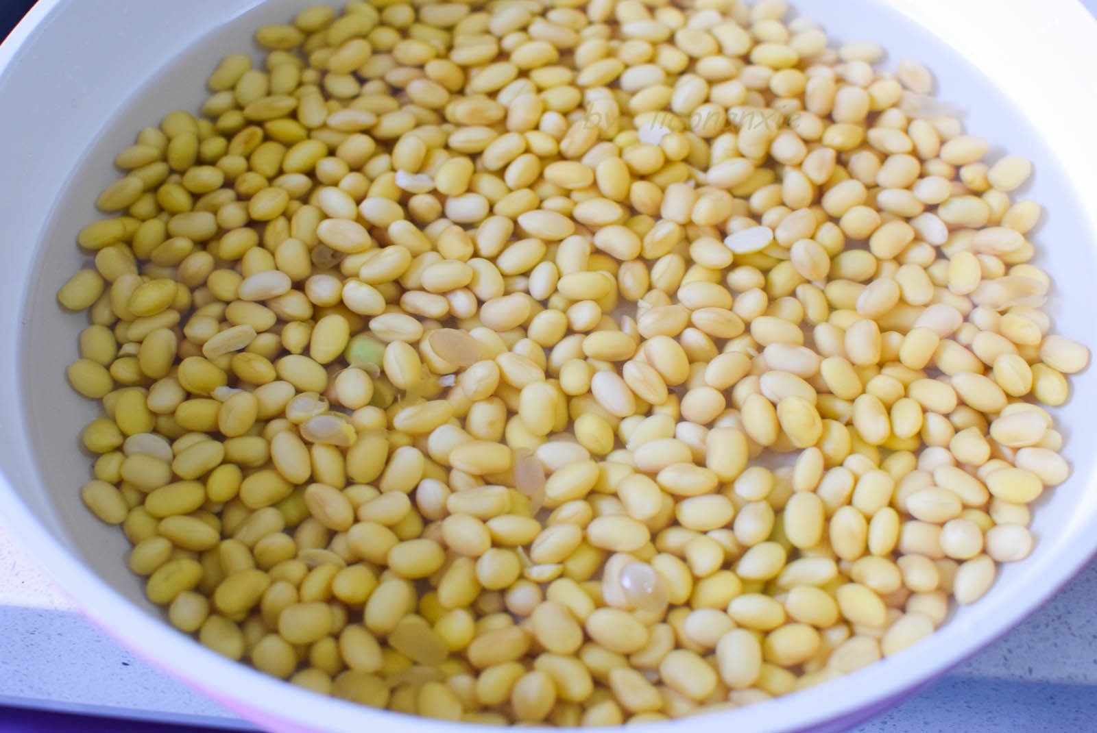 Ngâm 400g đậu nành trong nước sạch cho nở căng hạt. Mùa lạnh cần ngâm 10 tiếng trở lên, mùa nóng thì nên thay nước thường xuyên để tránh bị chua.